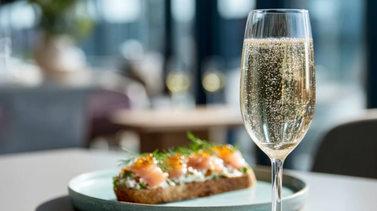 Champagneglas med bubblor bredvid toast skagen på en tallrik