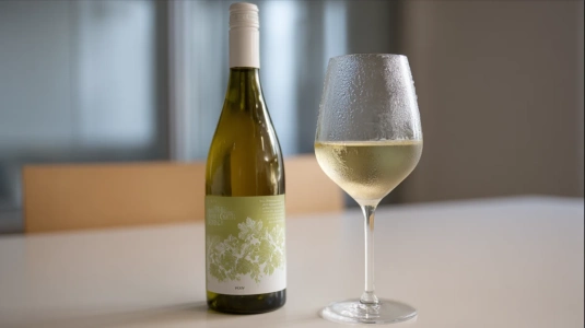 Flaska tysk riesling med ett kylt glas på en enkel yta