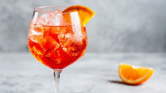 Aperol Spritz i ett stort vinglas med isbitar och apelsinskiva