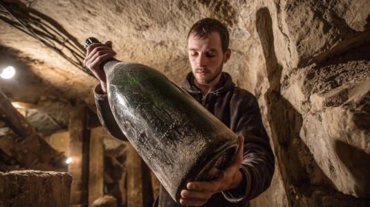 Storformatflaska champagne i jeroboam-storlek hanteras för hand i källare