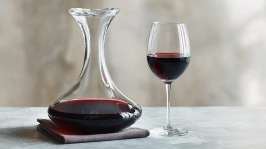 Mörkt rödvin i en glaskaraff bredvid ett vinglas med koncentrerad färg