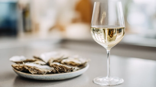 Glas ljust Chablis-vin med citrusgul ton på en enkel yta
