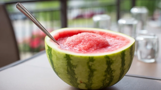 Urholkad vattenmelon fylld med frozen margarita och en slev