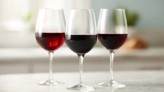 Tre glas rött vin i olika nyanser sida vid sida