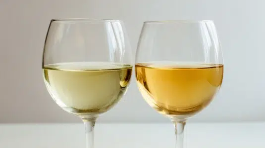 Två glas vitt vin sida vid sida – ett blekare Chablis och ett gyllene fatlagrat Chardonnay