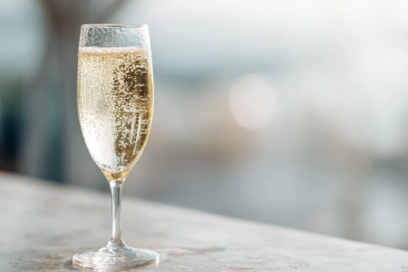 Glas med crémant och bubblor mot neutral bakgrund