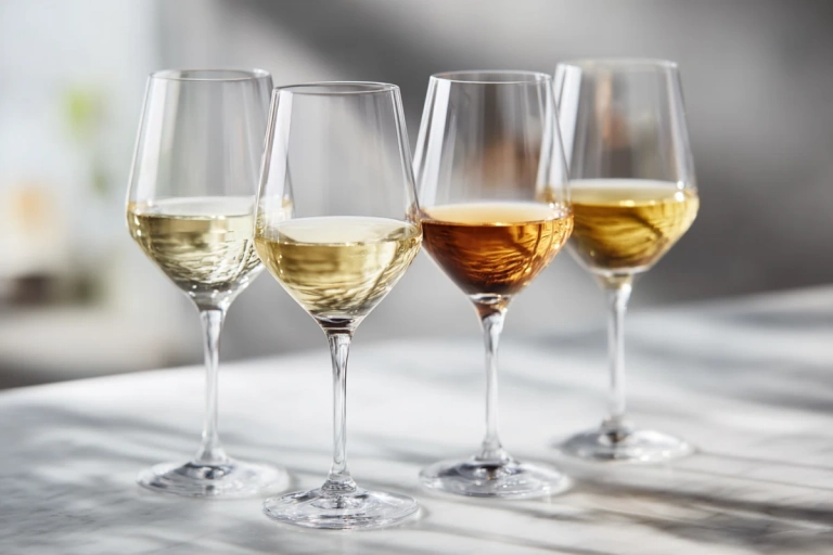 Fyra glas vitt vin i olika nyanser från ljusgult till gyllene