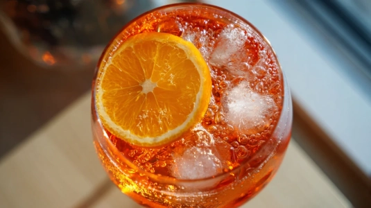 Tunn apelsinskiva som flyter bland isbitar och bubbel i en färdig Aperol Spritz