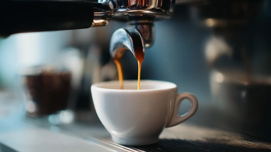 Färsk espresso med crema rinner ner i en kopp från en espressomaskin
