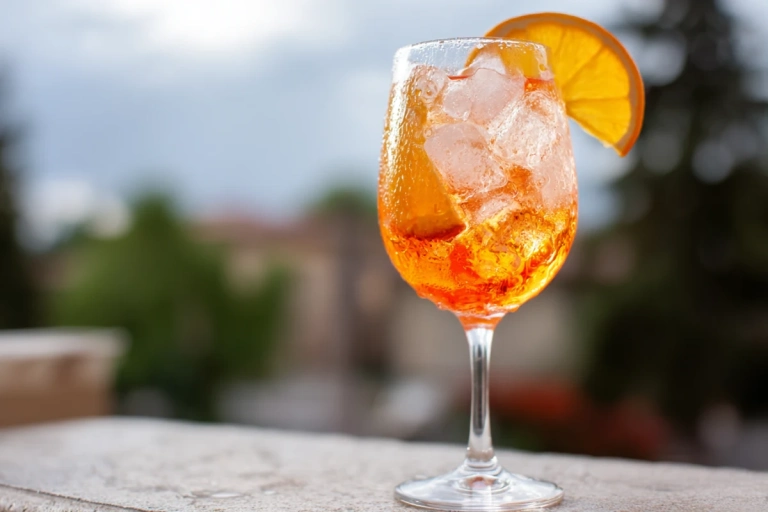 Cava Aperol spritz i ett stort vinglas med is och apelsinskiva