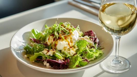 Varm chèvresallad serverad bredvid ett glas vitt vin