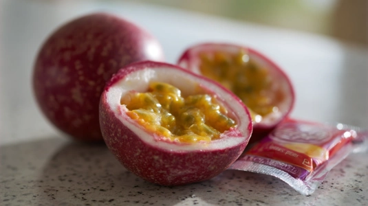 Färsk passionsfrukt med skrynkligt skal bredvid fryst passionsfruktspuré