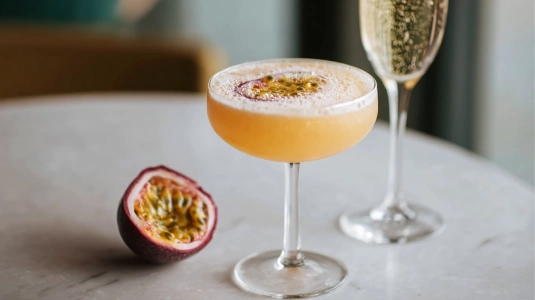 Halv passionsfrukt som flyter på en pornstar martini i coupeglas