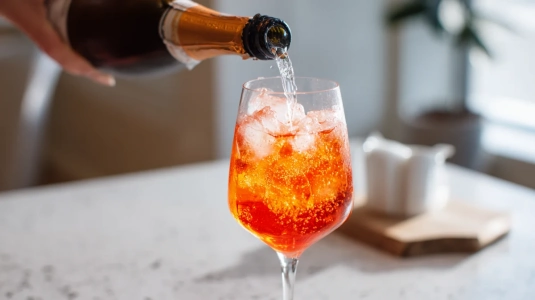 Cava hälls försiktigt längs glasets insida över Aperol och is
