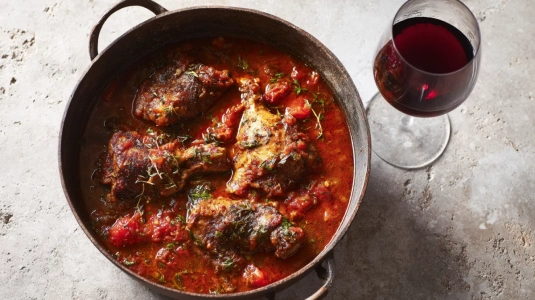 Kyckling cacciatore i tomatbaserad sås med ett glas rött vin