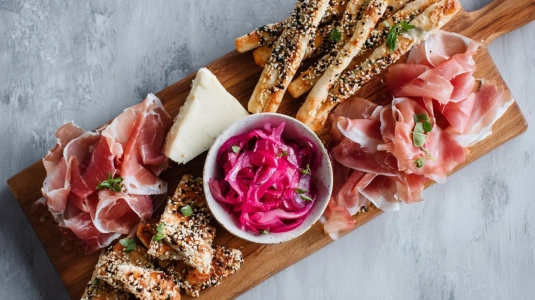 Mingelbricka med prosciutto, brie, picklade rödlökar och grissini