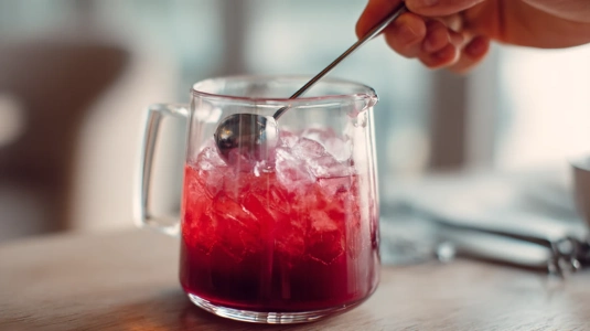 Barsked som rör runt i ett mixglas fyllt med is och röd Negroni-blandning