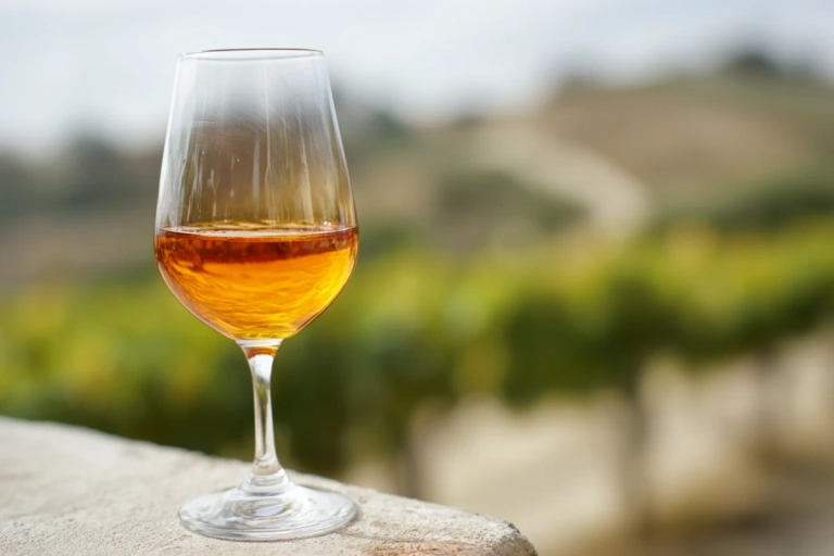Glas med bärnstensfärgat orange vin på ett enkelt bord