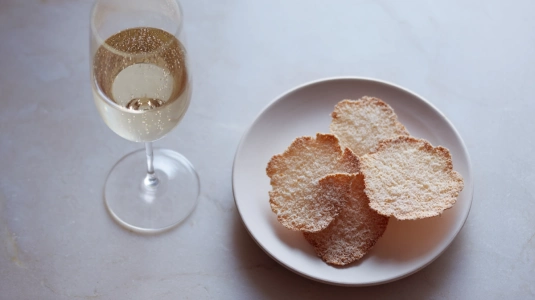 Parmesanchips bredvid ett glas champagne