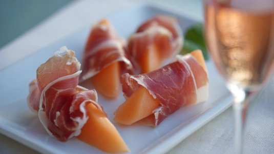 Prosciutto lindat runt cantaloupe-melon på serveringsfat