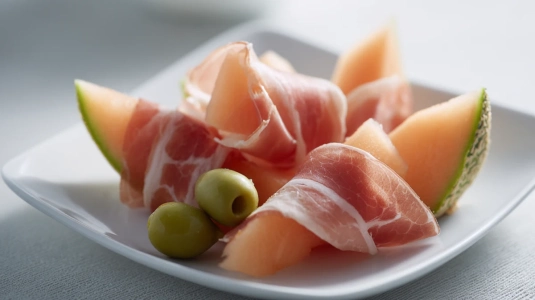 Melonskivor lindade med parmaskinka på en tallrik