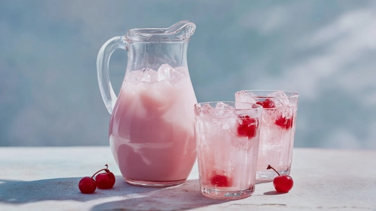 Glaskanna med Rosa Pantern-blandning bredvid fyllda highballglas