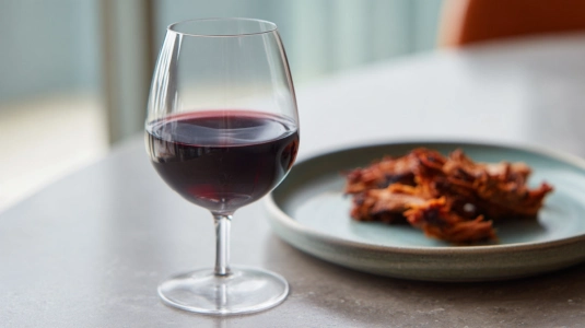Glas mörkt rödvin bredvid en tallrik med pulled pork