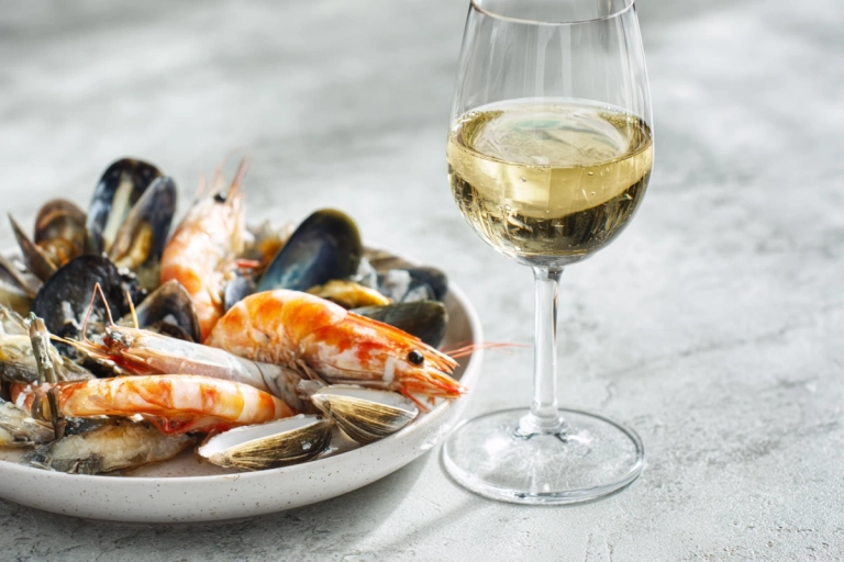 Glas vitt vin bredvid en tallrik med skaldjur