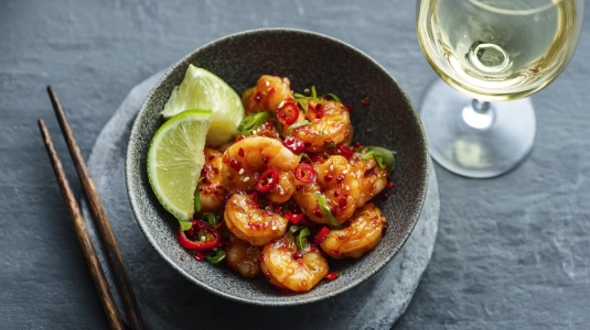 Wokade räkor med chili och limeklyftor i skål